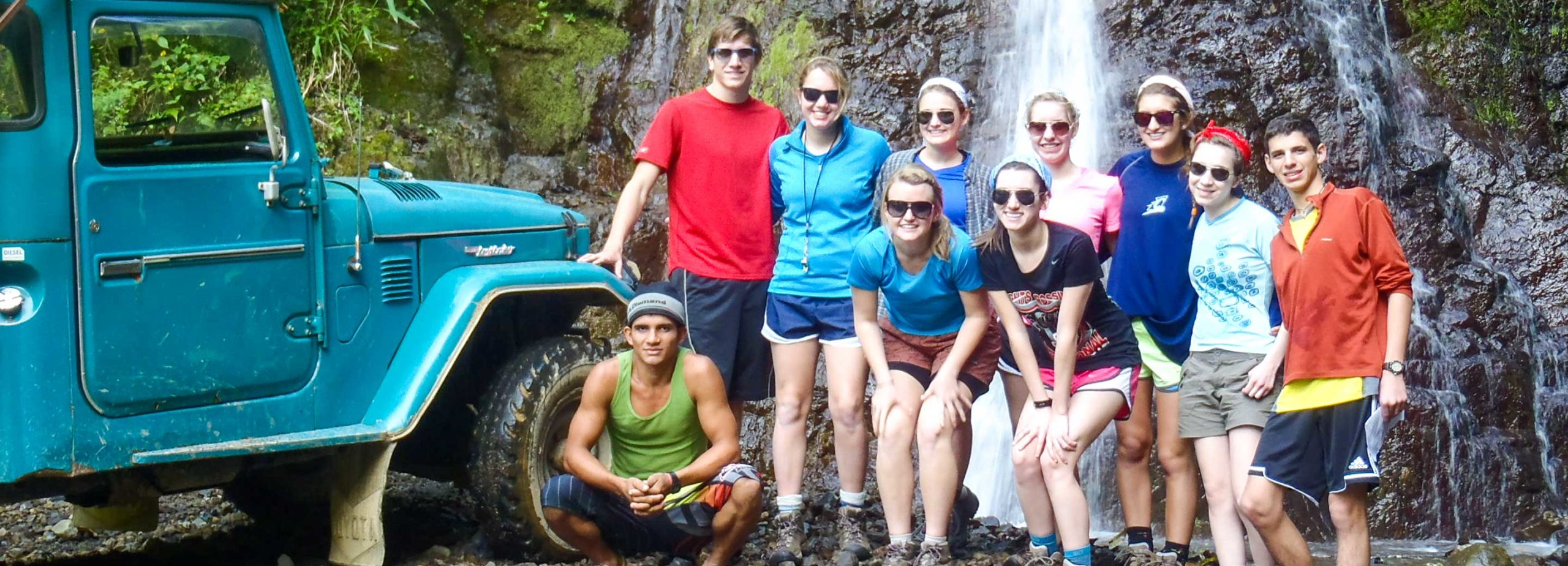 Group of teens standing by truck and waterfall